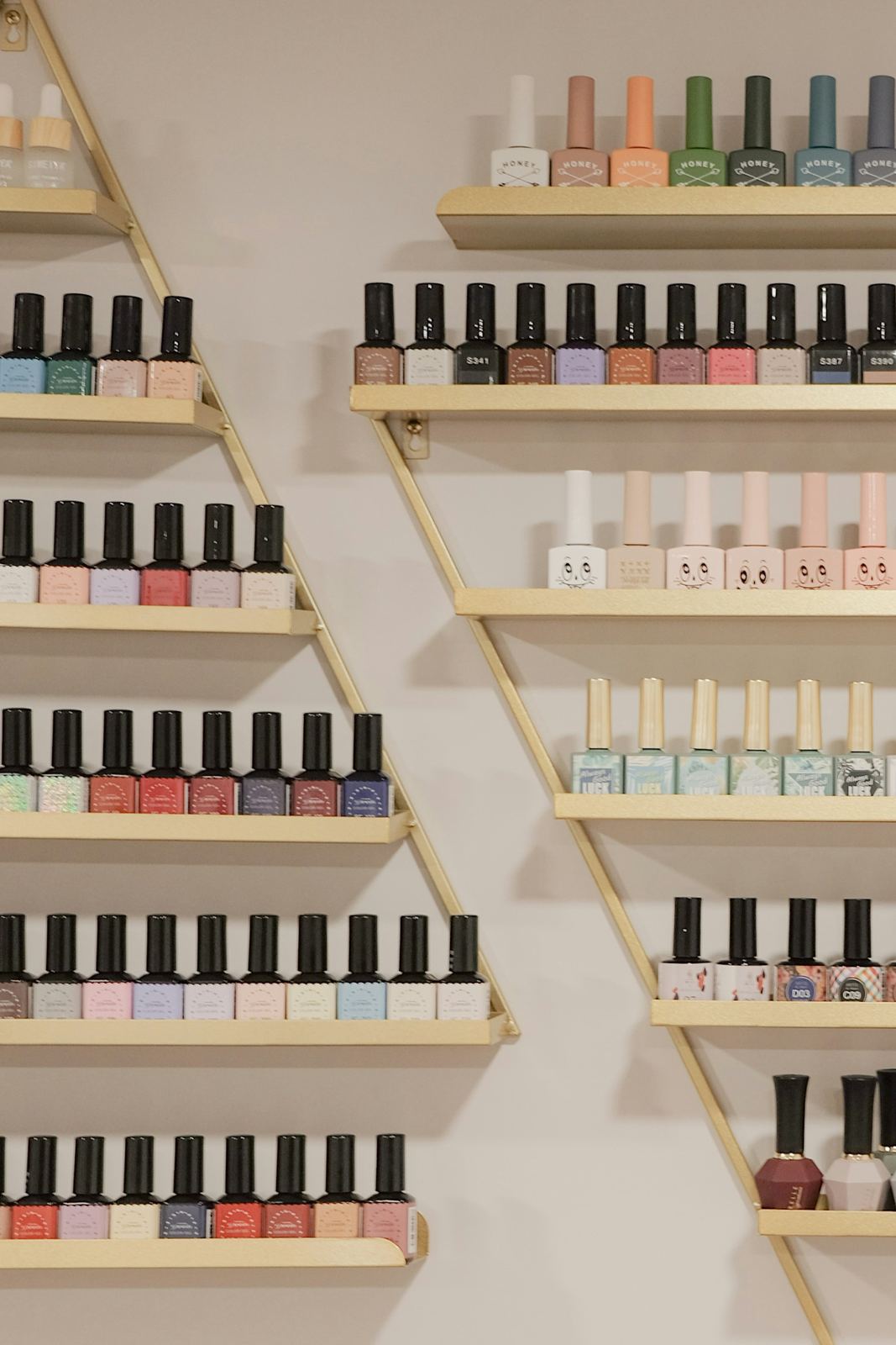 Rows of nail polish bottles on gold shelves in the studio