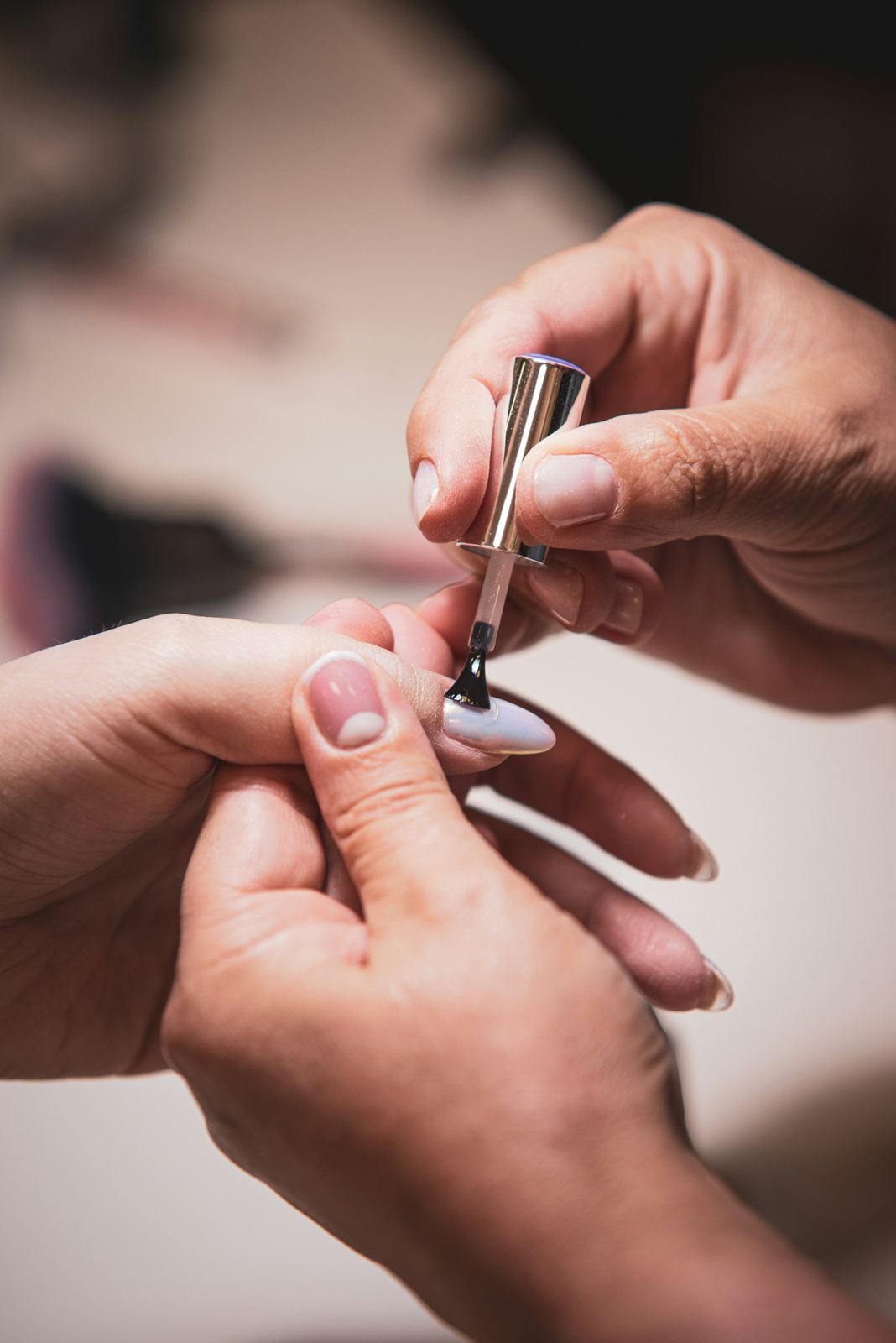 A technician carefully painting a client's nail with a fine brush