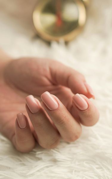 Short, soft pink overlay nails on a white rug