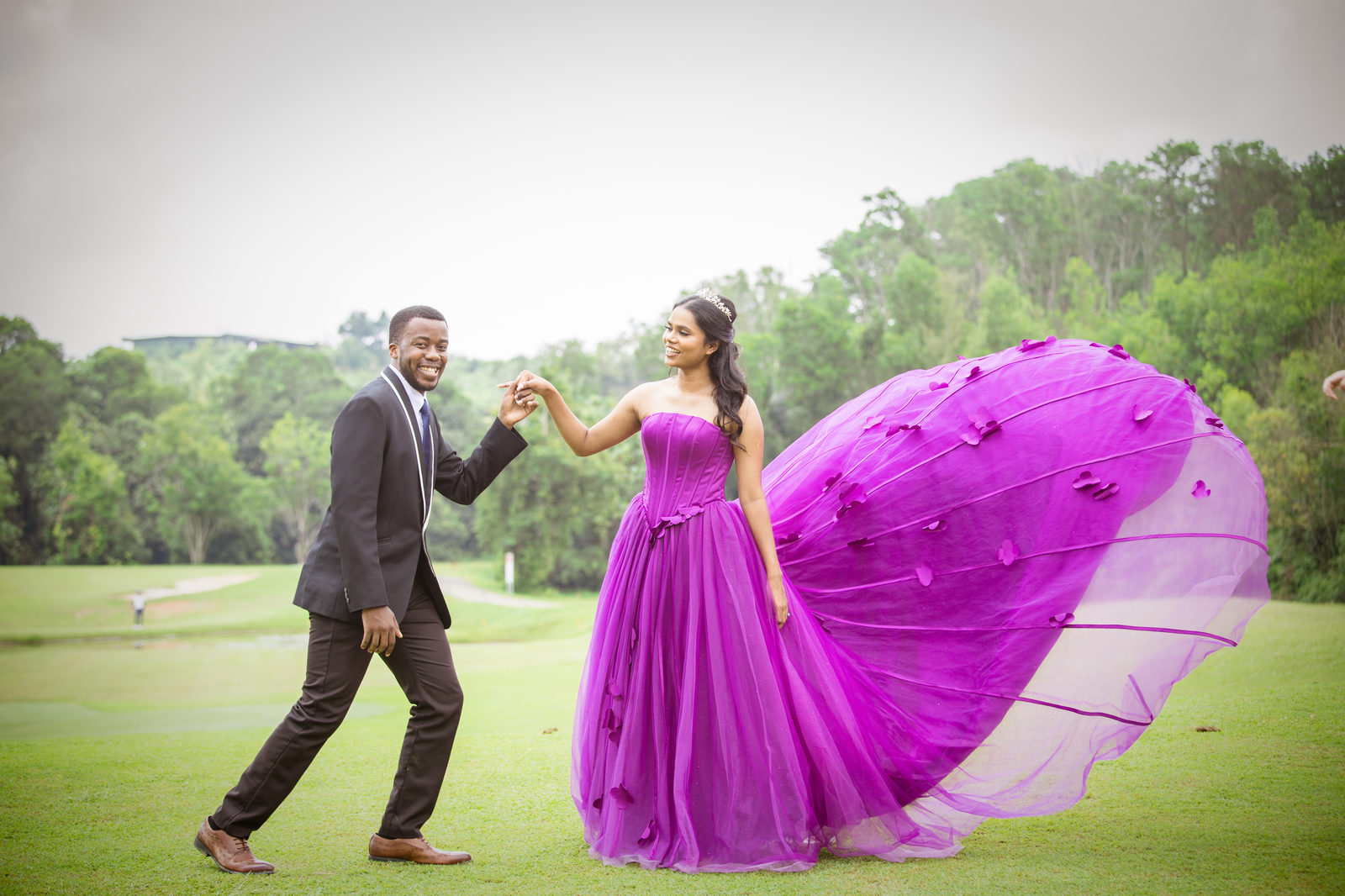 Munshya leading Aghalya by the hand across a lawn, her magenta gown billowing behind her
