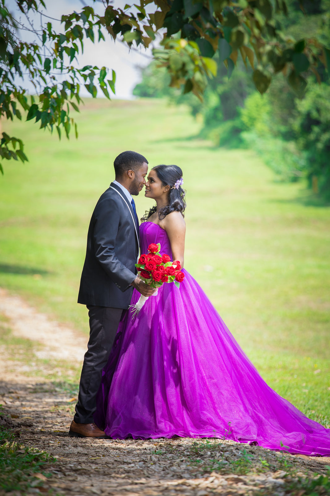 Munshya and Aghalya nose to nose on a leafy path, she holds red roses