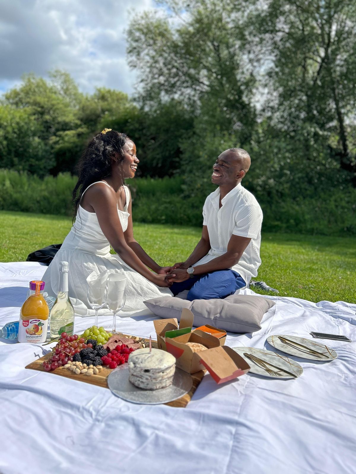 Makanaka and Davidson having a picnic on a white blanket in a garden