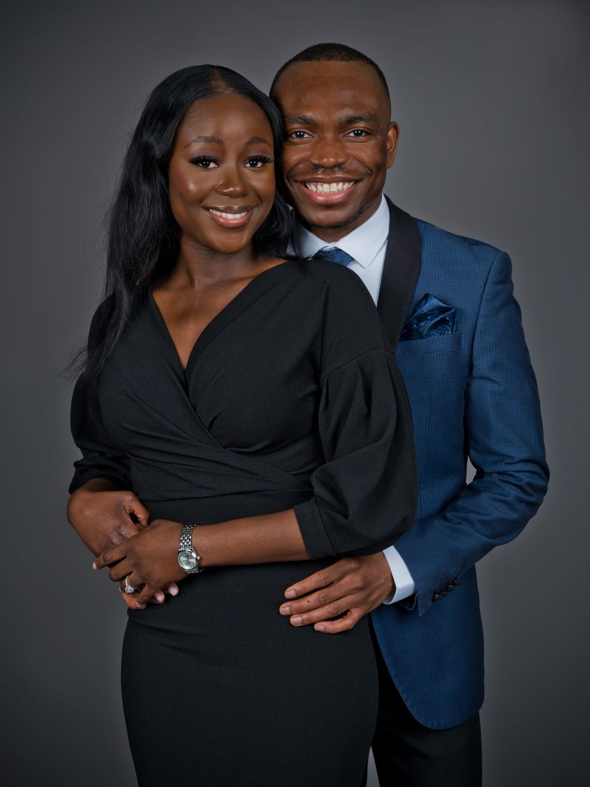 Makanaka in a black dress and Davidson in a blue suit, smiling in a studio