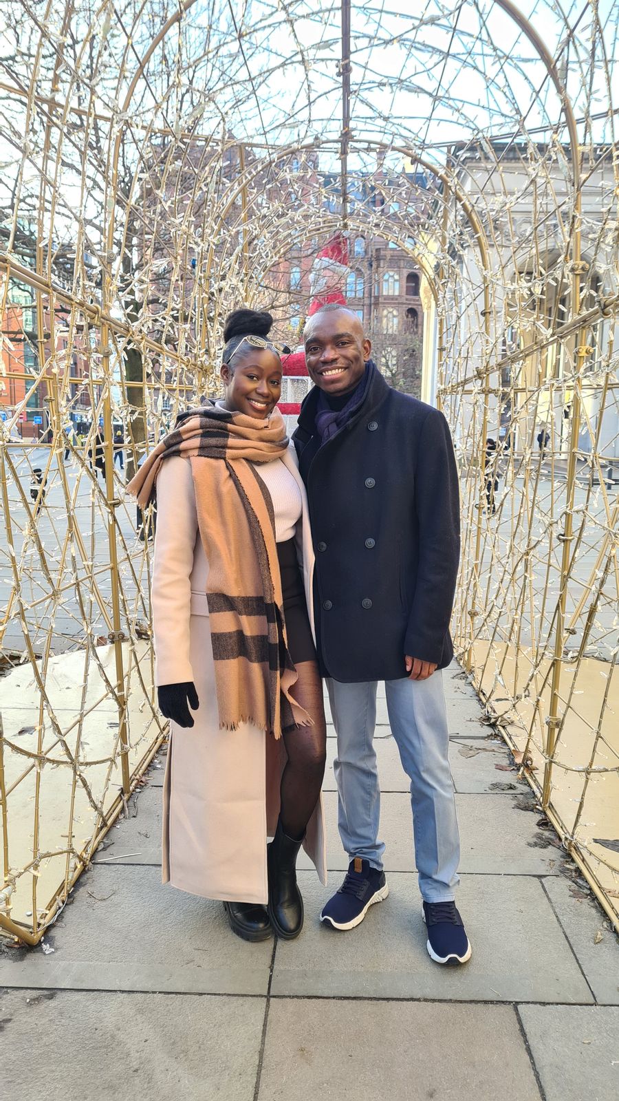 Makanaka and Davidson in winter coats under an arch of lights