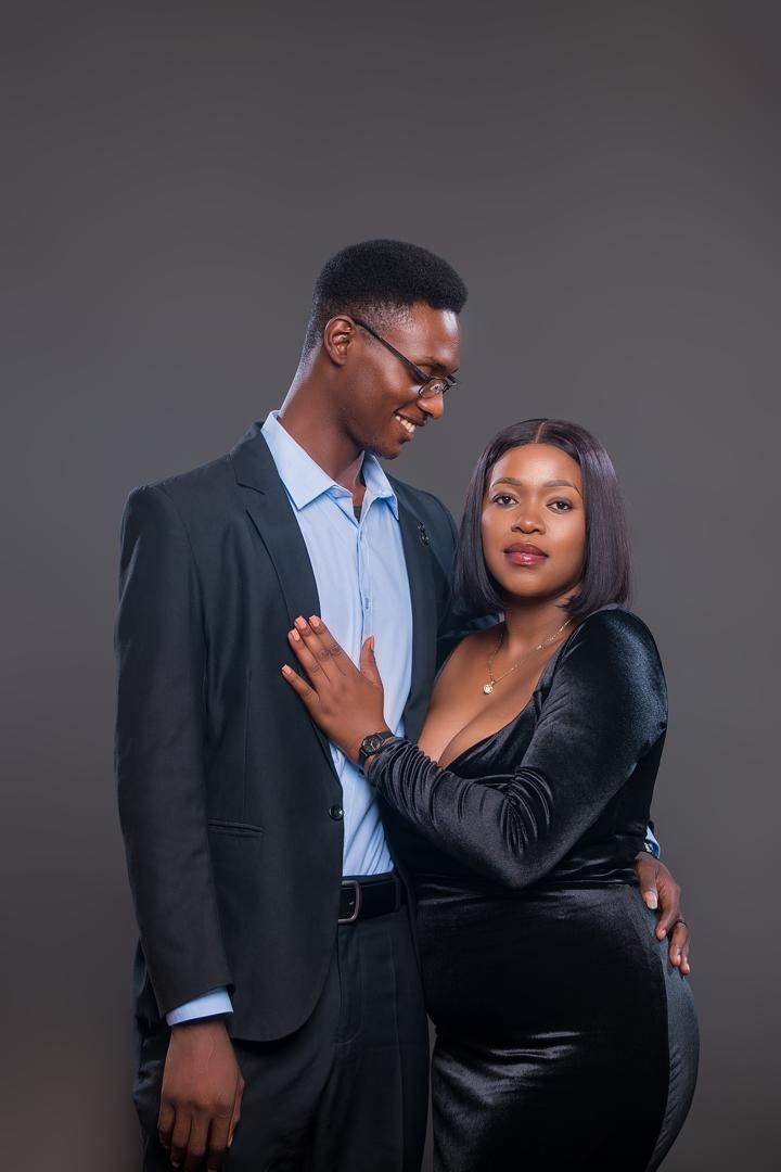 Mwaka resting her hand on Elijah's chest as they smile at the camera