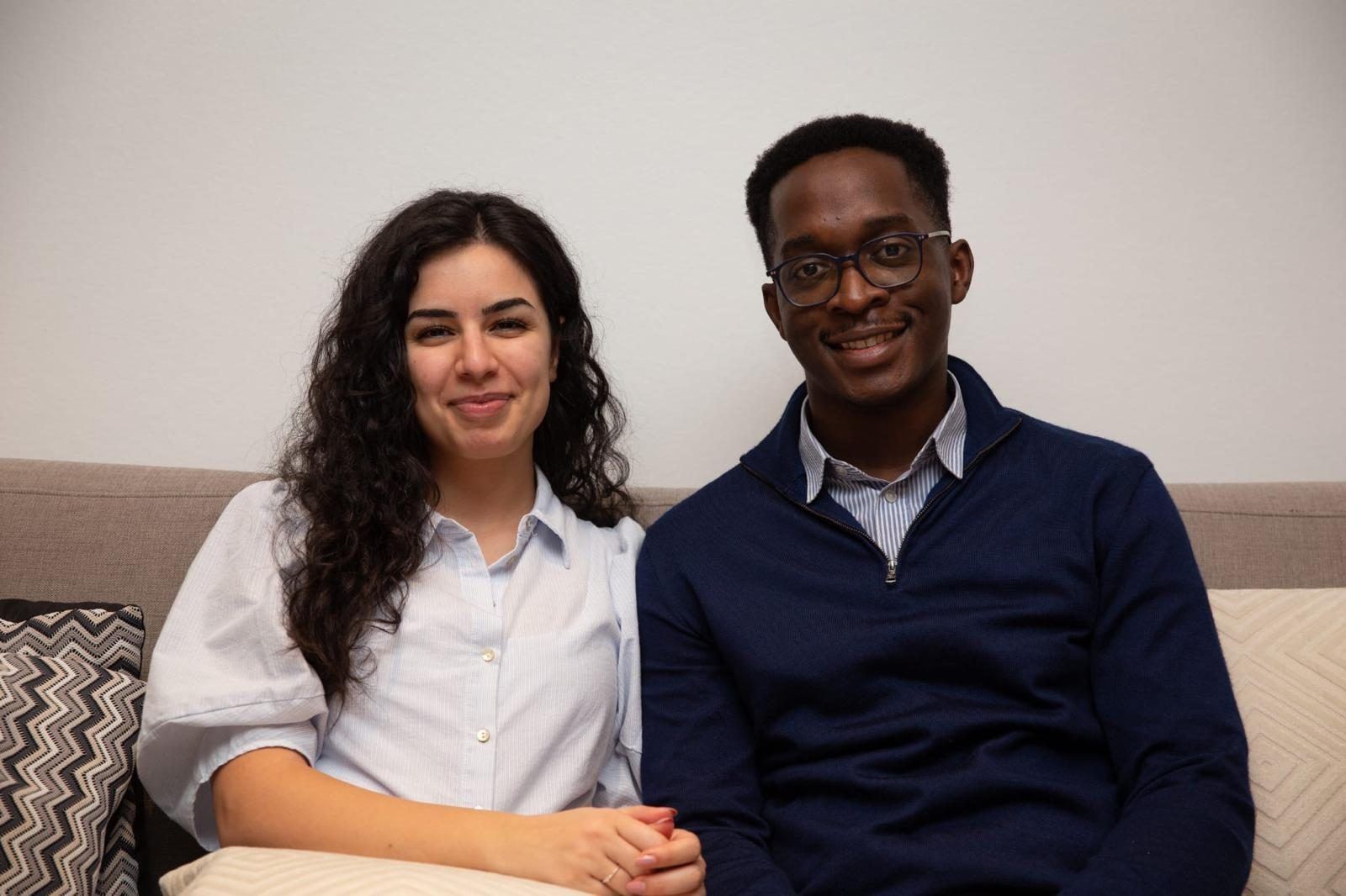 Yasmin and Mpaala sitting together on a sofa, smiling