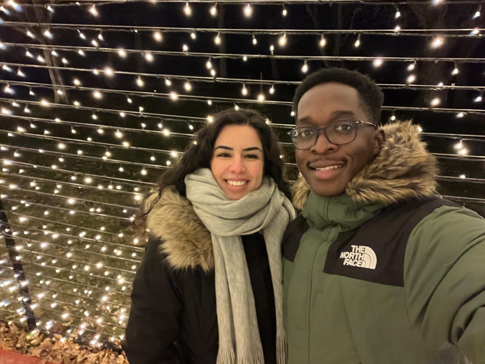 Yasmin and Mpaala smiling under a canopy of fairy lights