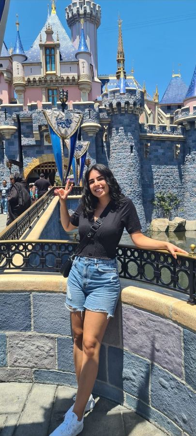 Yasmin waving in front of a fairy-tale castle
